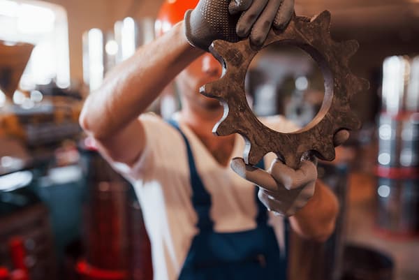 A metal worker handling a gear