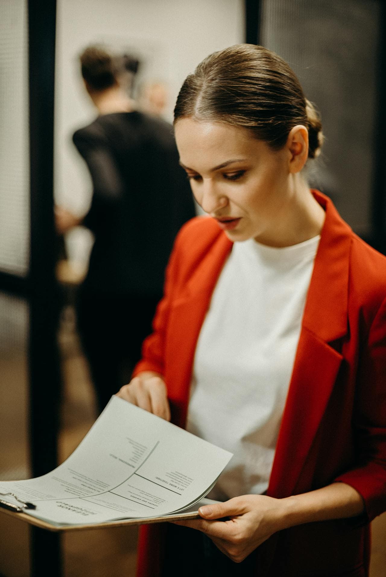 A woman in a red business jacket review a document