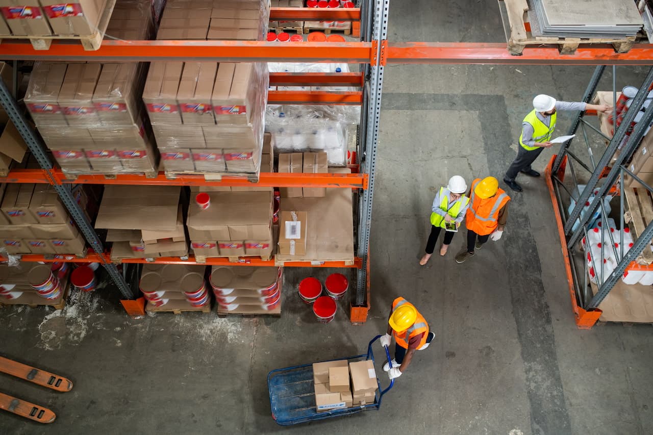 One of warehouse workers pushing cart with boxes