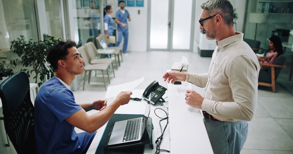 Healthcare Admin worker handling paperwork to a patient