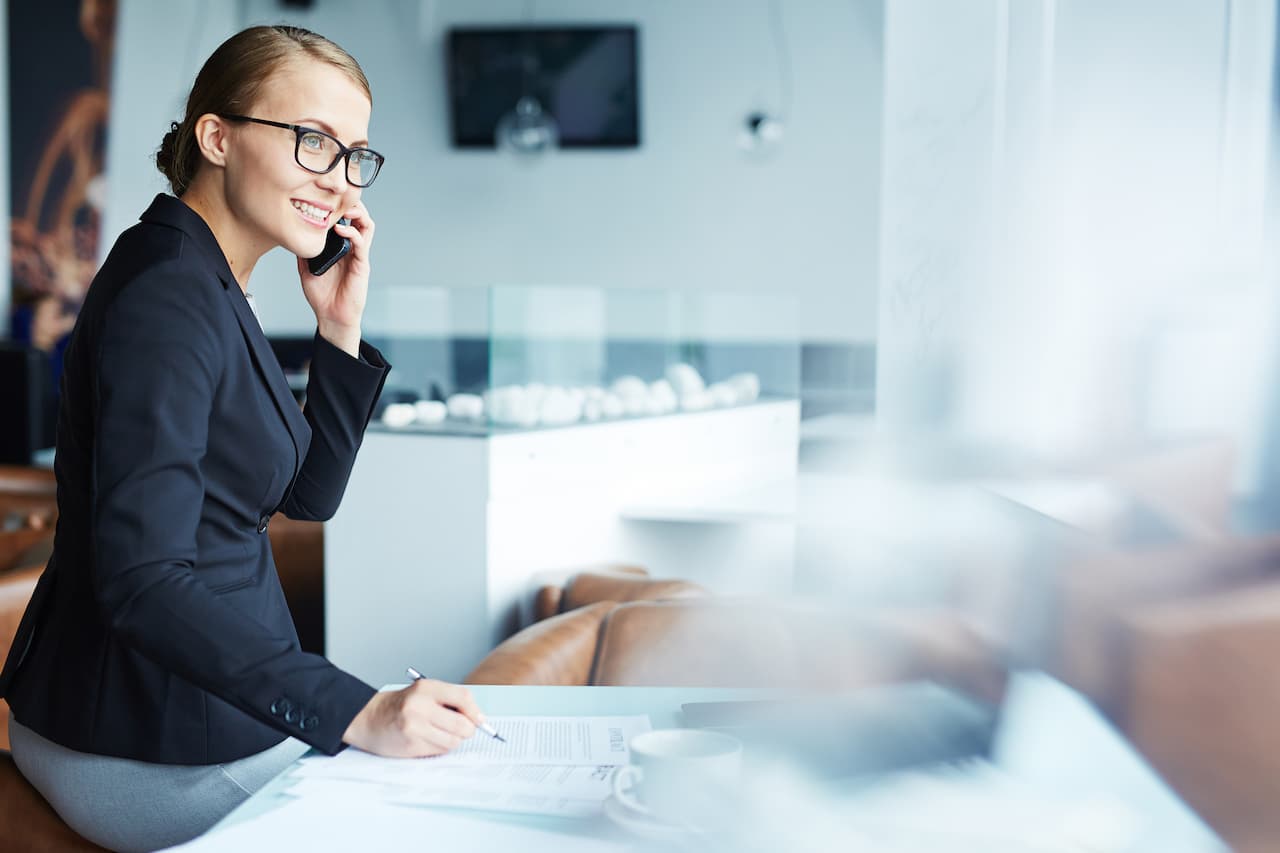 Female Internal Sales Consultant Answering Phone in Office Writing Notes