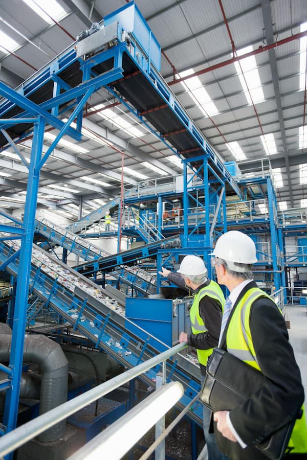 Vertical Shot Of Businessmen Watching Plastic On Conveyor Belt In Recycling Plant