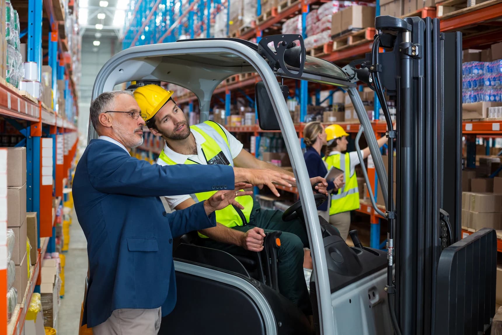 A warehouse manager instructing a forklift operator