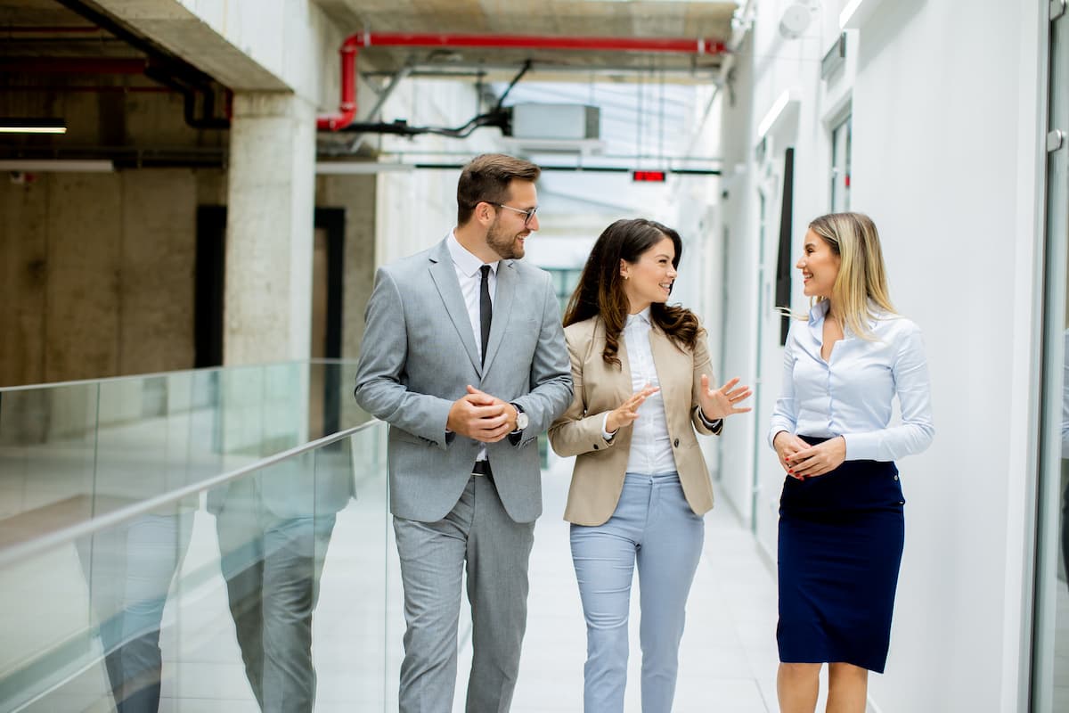 three sales professionals walking along a building hallway