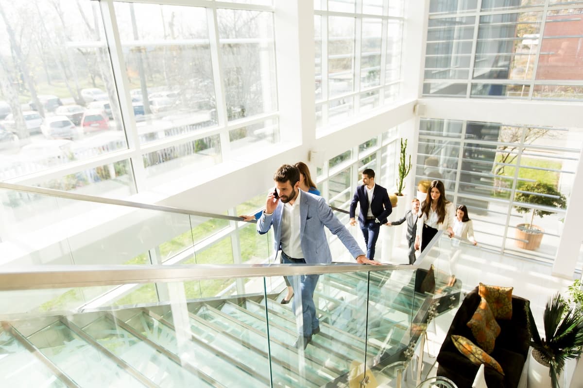 A team of corporate workers walking up the stairs of a modern building