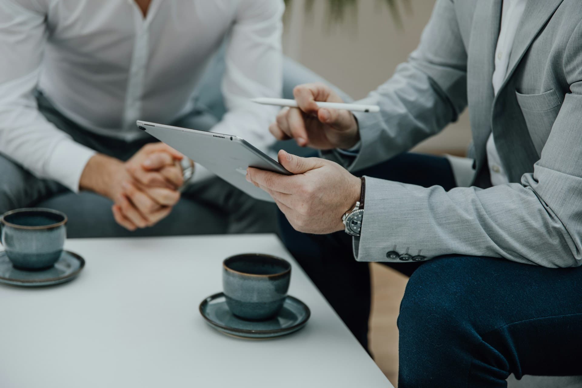 Details of two business men reviewing information on a tablet