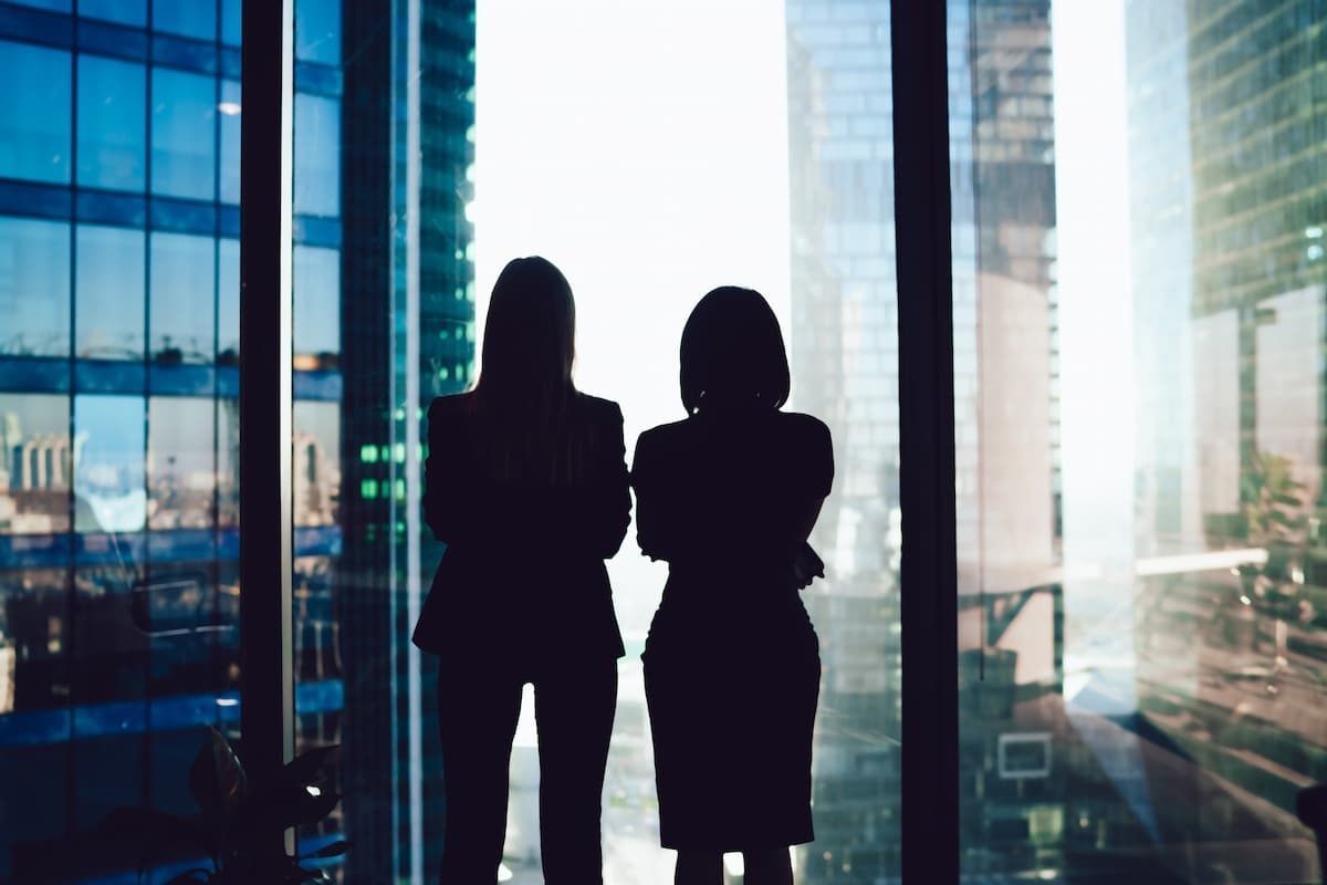 Two business women looking out the window in a modern glass building