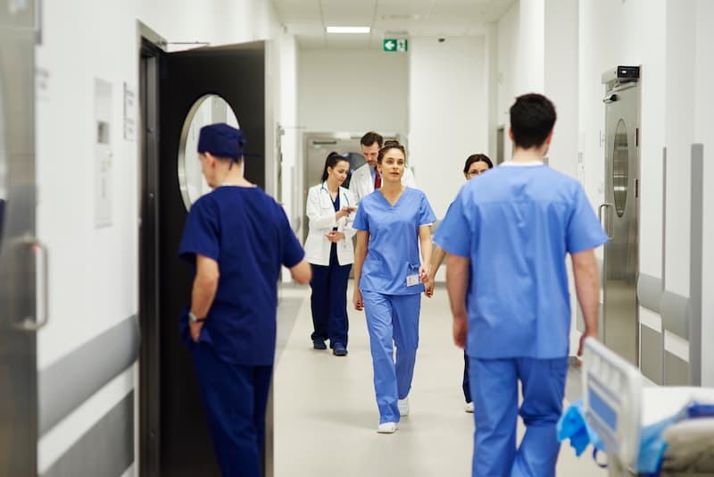nurses and doctors walking through a corridor in hospital
