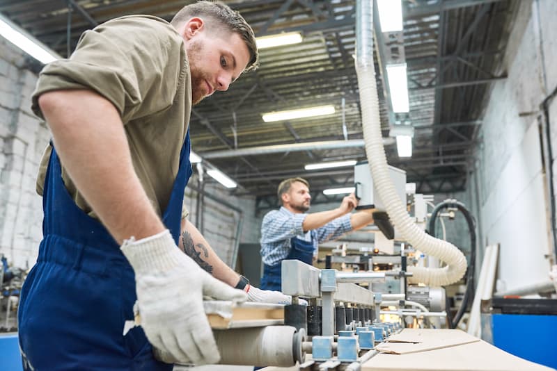 two trade workers using machines in joinery shop