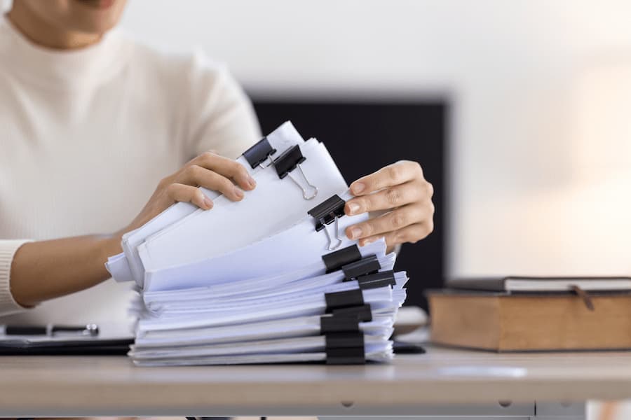 Woman Working With Stacked Documents on Desk