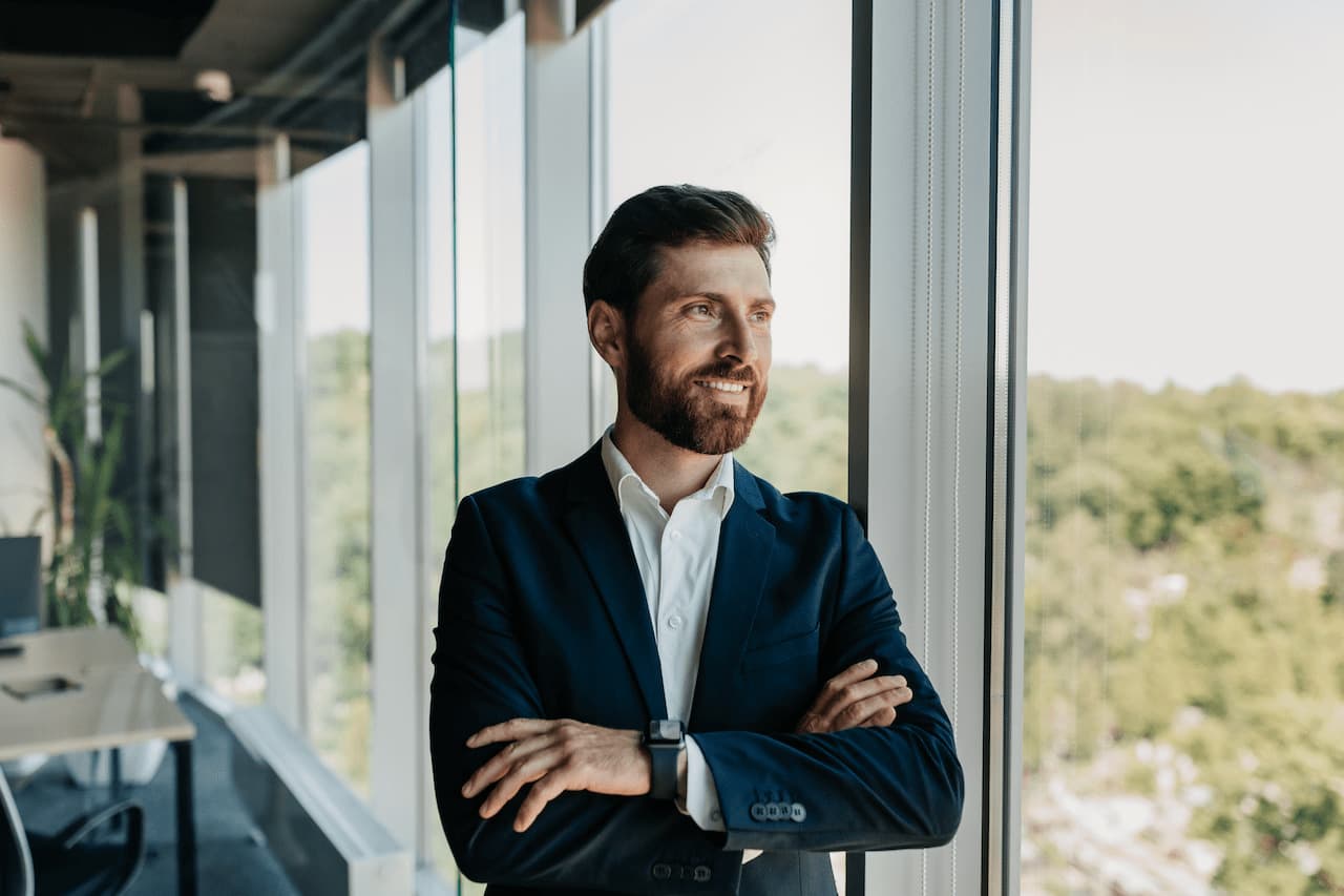 Businessman Stands Near Window in Modern Office