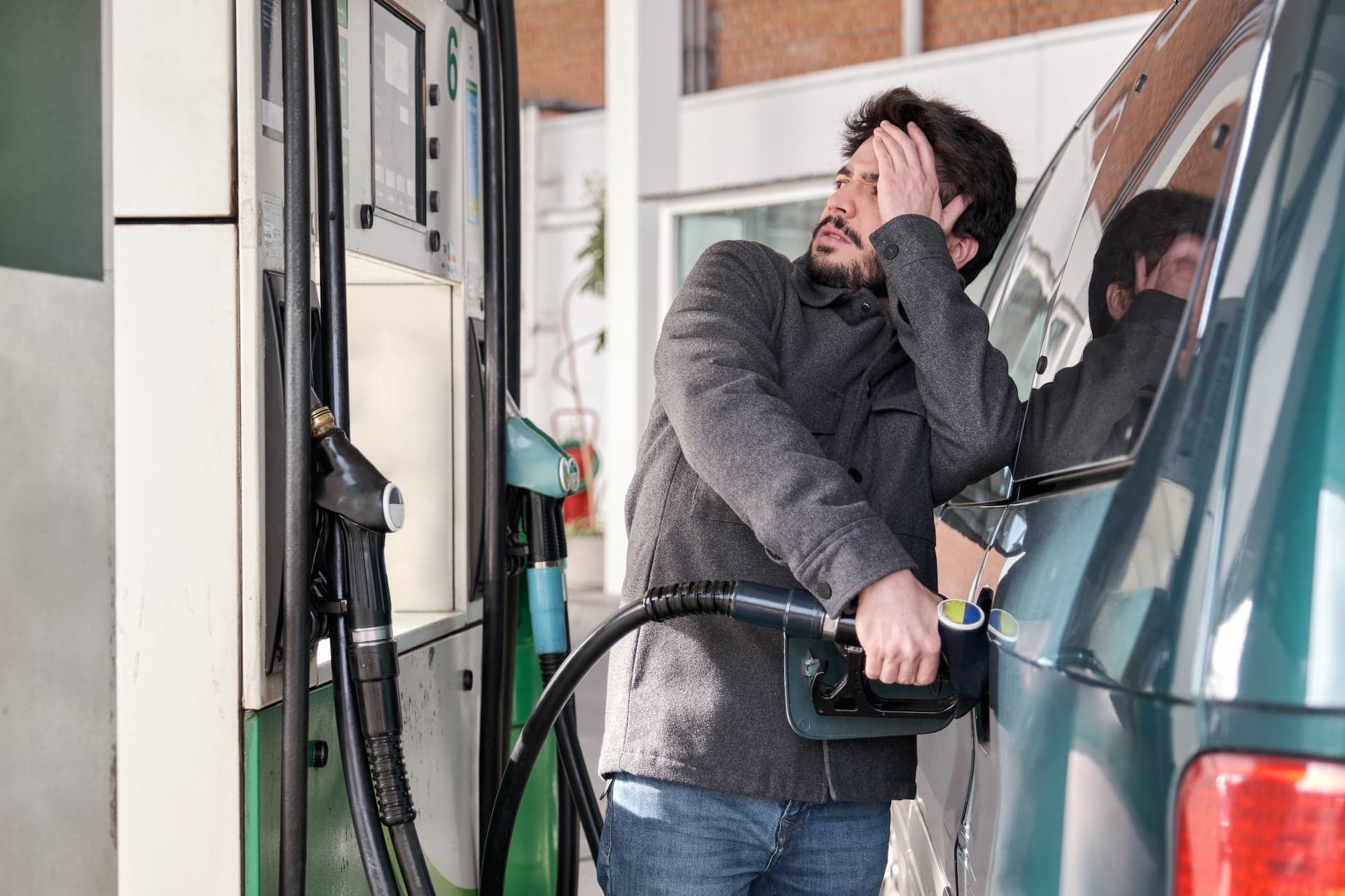 Man refuelling his car and looking stressed