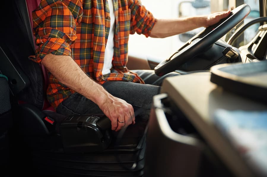 Close up view, sitting inside. Young truck driver in casual clothes