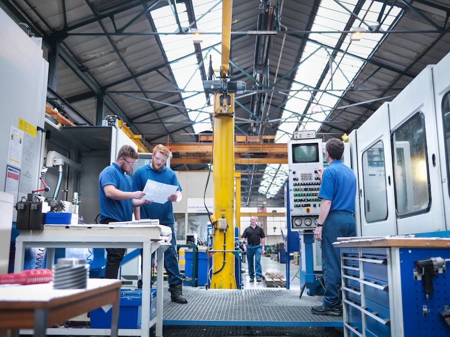 Engineers at lathe workstation in engineering factory