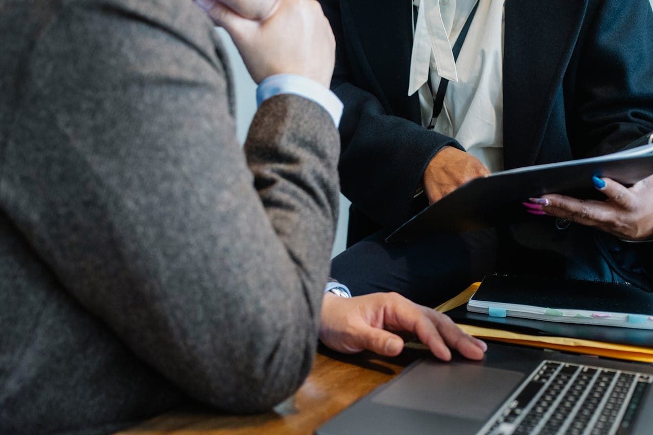 Close-up of two professionals in formal clothing during a business meeting, discussing documents