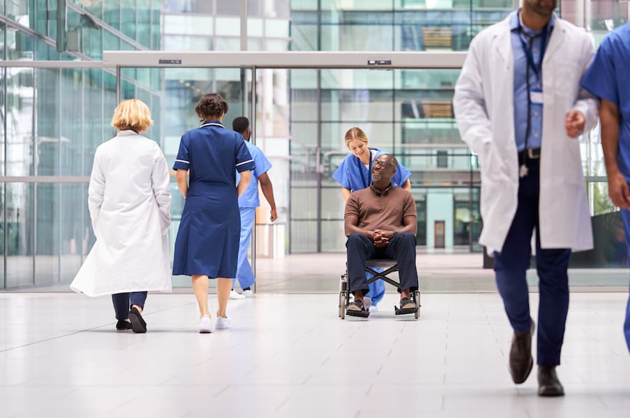 Female nurse wheeling a patient into a hospital
