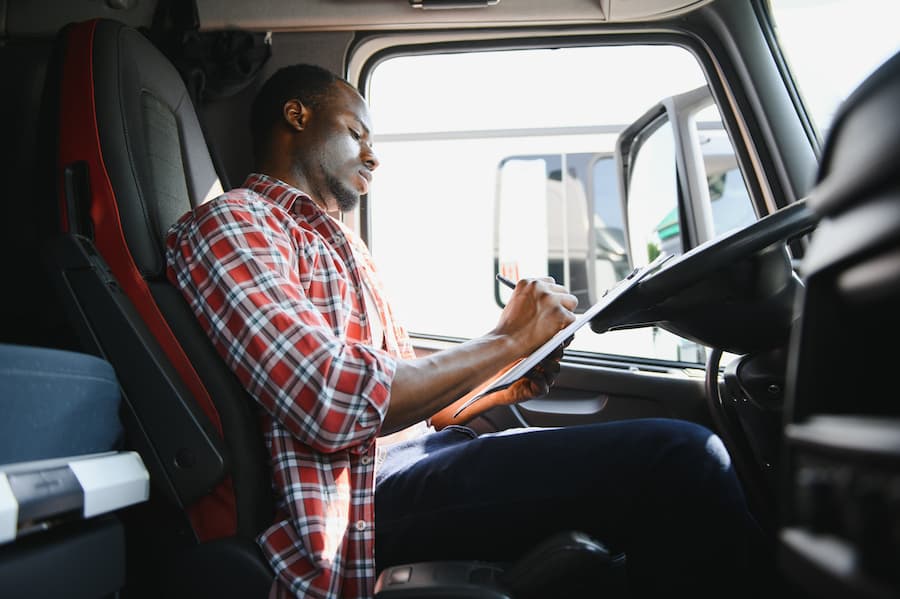 Man in Truck Cab Writing on Clipboard