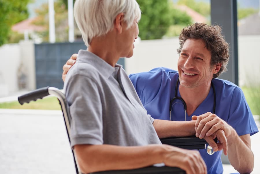 Nurse, senior woman and wheelchair with smile, elderly care and wellness for health in nursing home