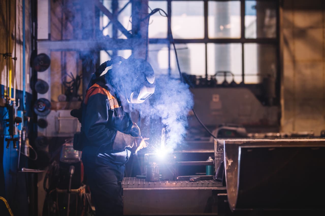 Worker welding in oxygen mask in a factory