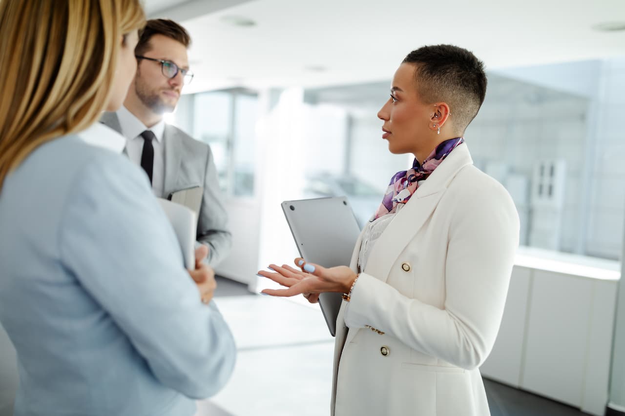 A group of business people stand in the hallway and discuss about problems in the company.