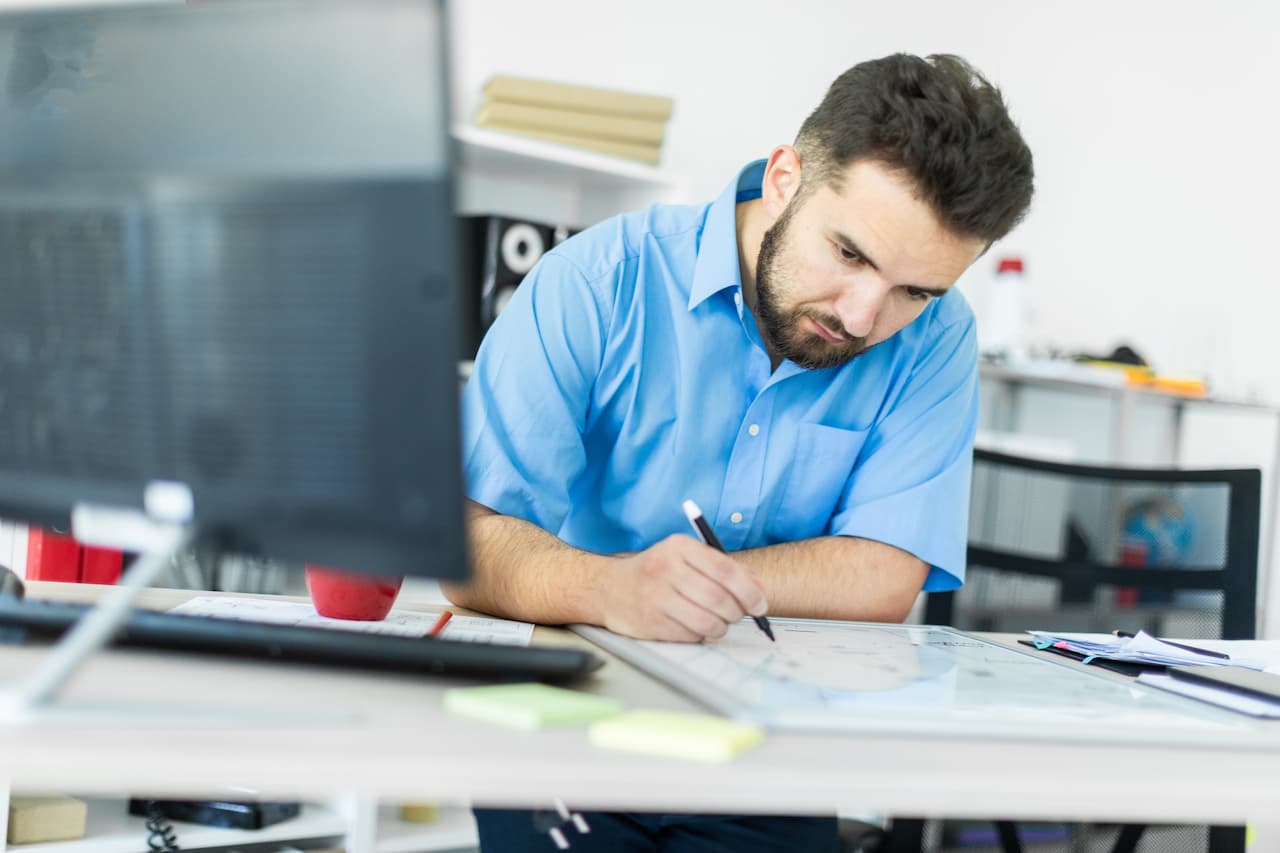 A young man standing in the office at a computer Desk and working with a magnetic Board