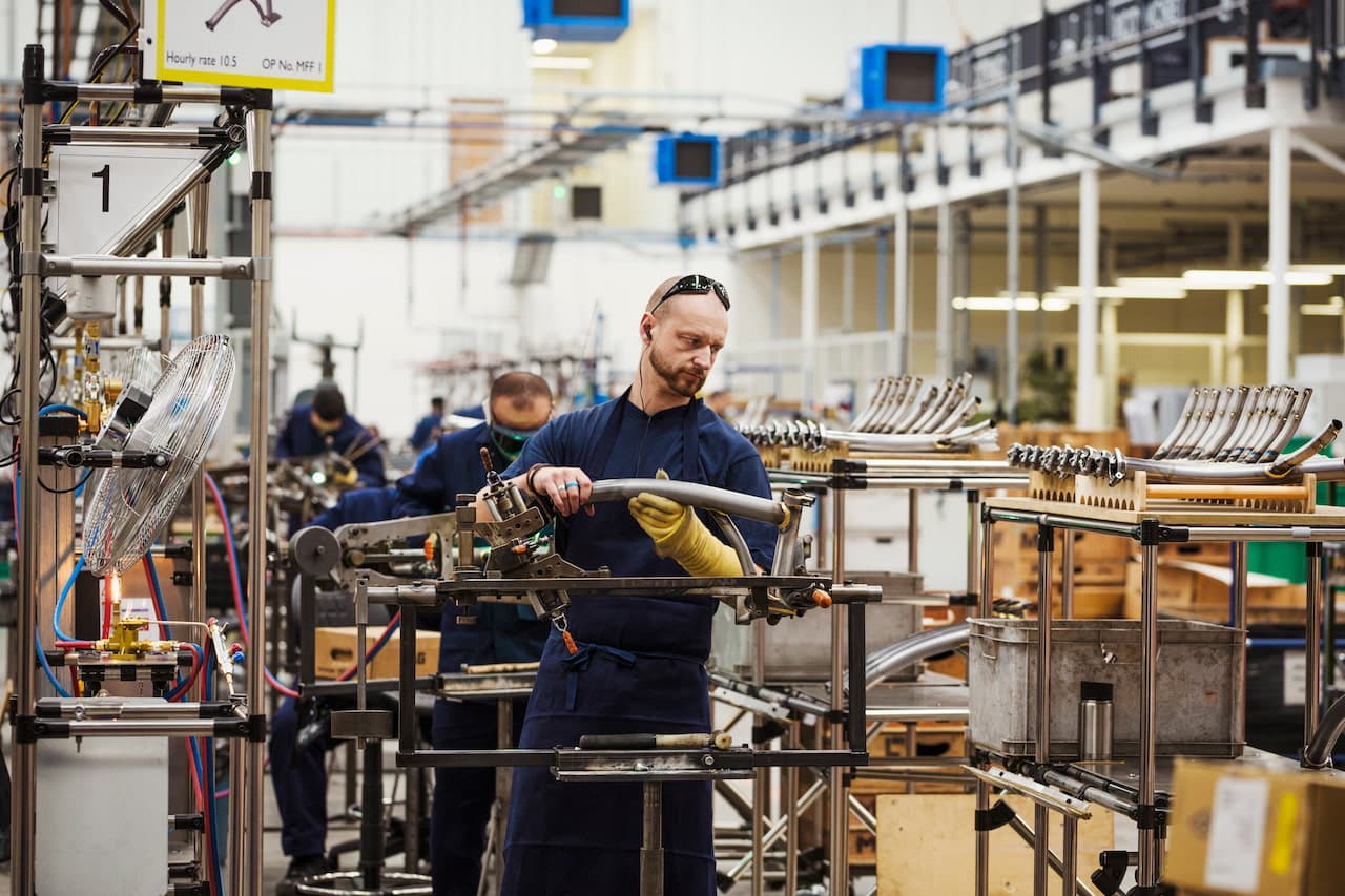 A man wearing one protective glove with sunglasses on his head, skilled factory worker working on