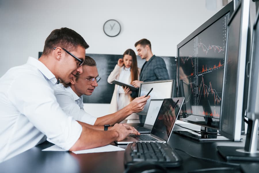 Attention to details. Team of stockbrokers works in modern office with many display screens