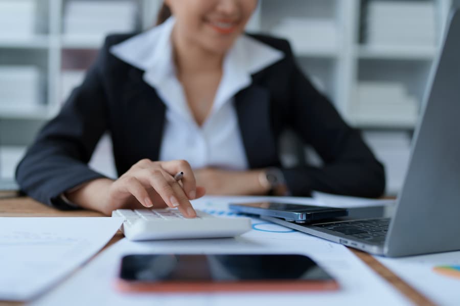 Businesswoman Using Calculator with Laptop and Mobile Phones