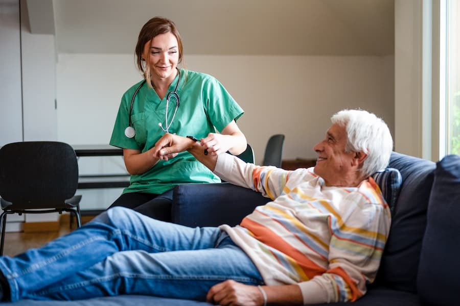 Caring Woman Examines Senior Man at His Home