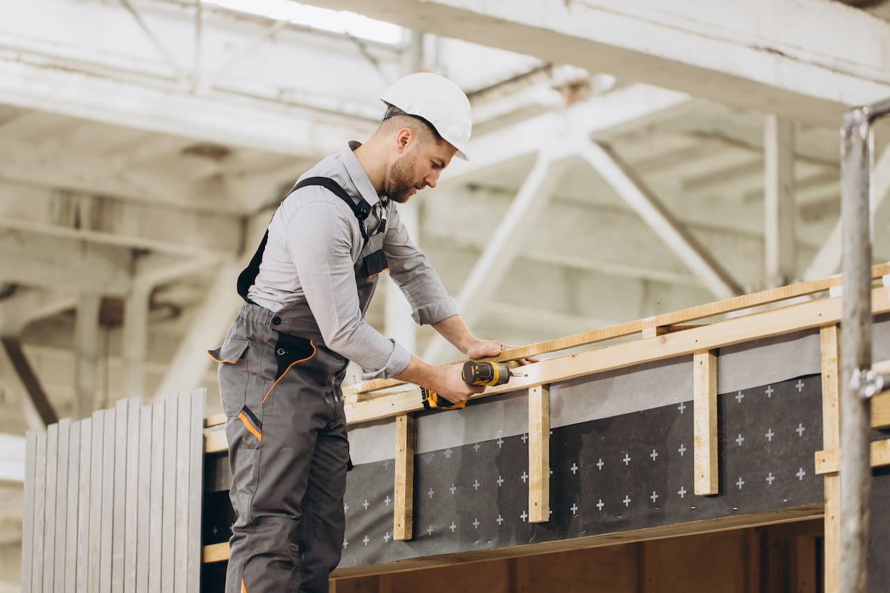 Construction worker building modular house using electric screwdriver