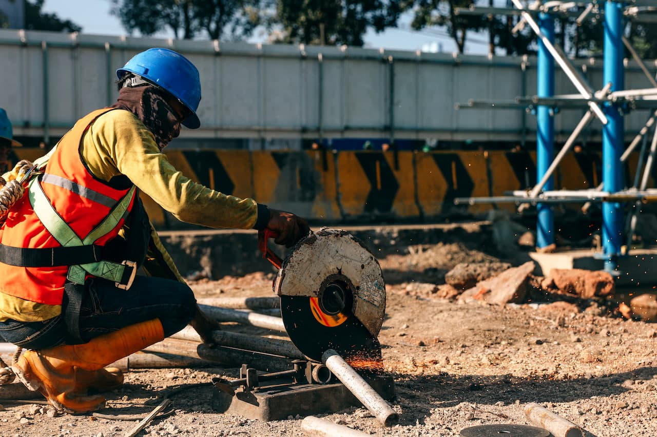Construction Worker Cutting Metal Pipe with Grinding Machine