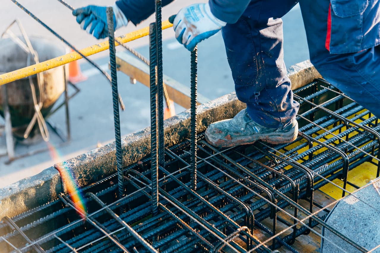 Construction Worker Securing Steel Rebar on Building Site