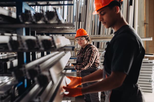 Factory workers checking window frame profiles in warehouse