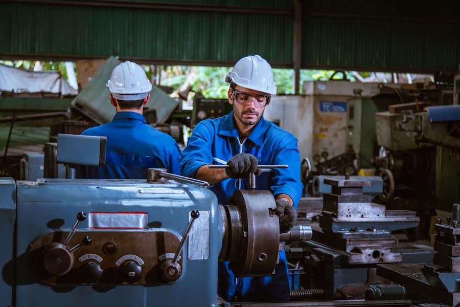 Factory Workers Operating Lathe Machine in Industrial Setting