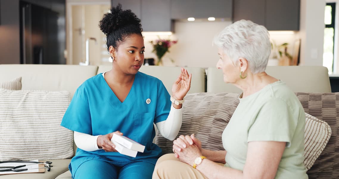 Female Caregiver Explaining Prescription Medication to a Senior Patient at Home