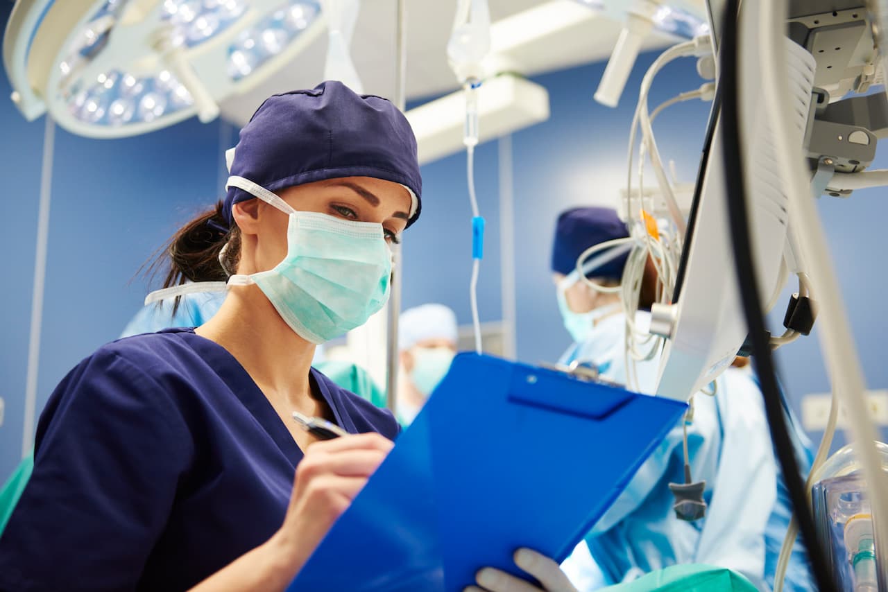 Day surgery enrolled nurse writes notes in operating room