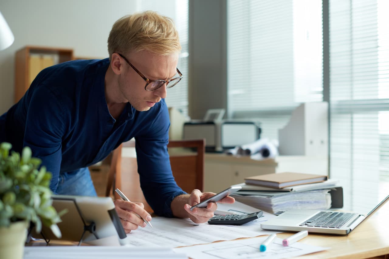 Financial Accountant Working at Desk with Mobile Phone