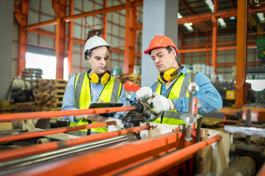 Foreman and trade assistant at factory site check up machinery