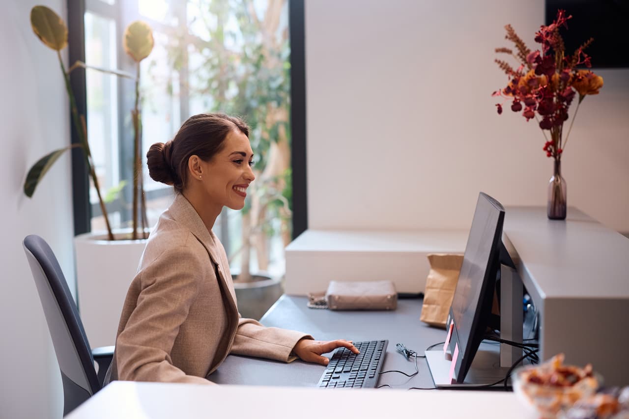 Happy businesswoman working at desktop PC in the office.