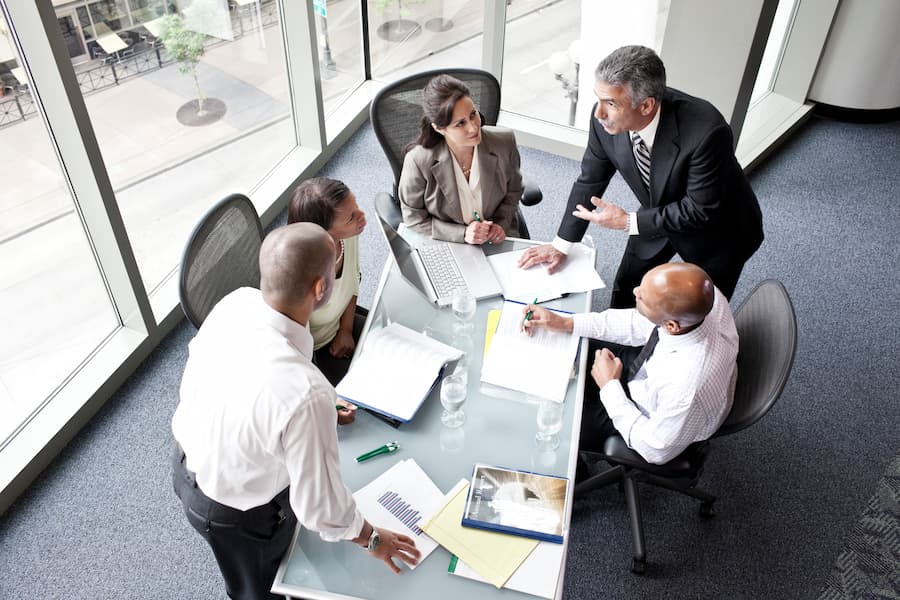 Male and female business people in a meeting at a conference table, overhead view