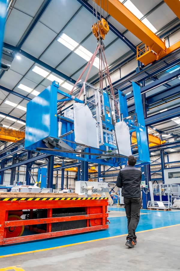 Man Overseeing Machinery Being Lifted Inside Factory