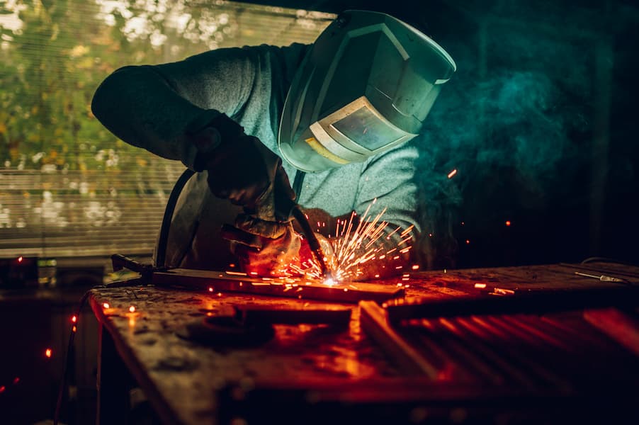 Man worker welding metal with welding machine in a factory or workshop