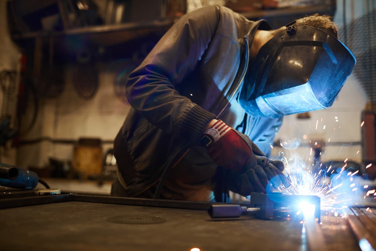Metal Worker Welding in Dark Workshop with Sparks