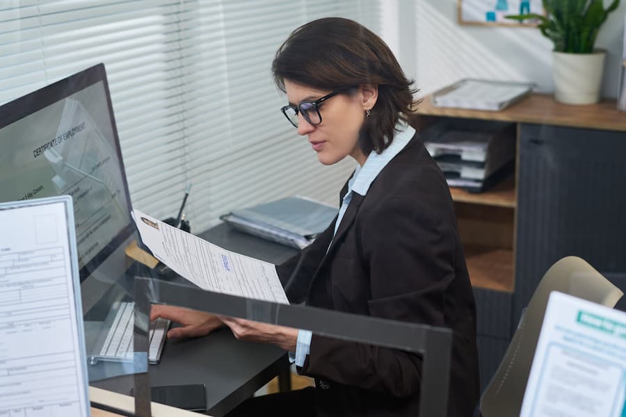 Middle Aged Woman Reviewing Documents at Visa Center Reception Desk