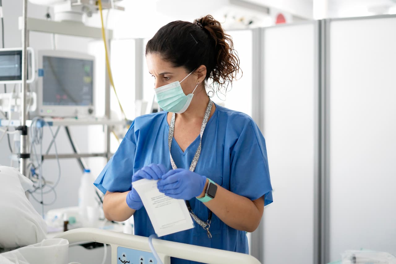 Nurse in mask preparing medical equipment in hospital icu