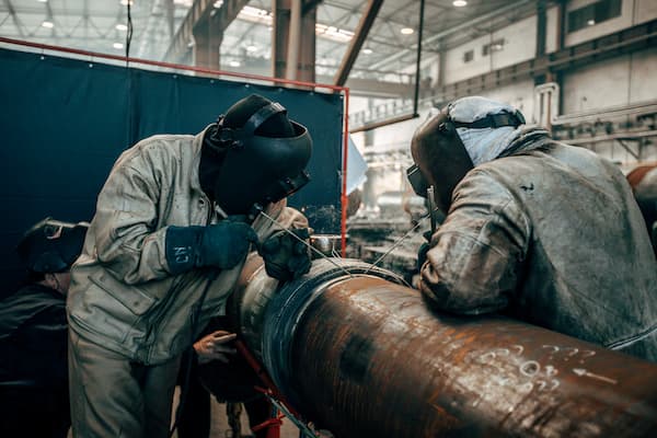 Shallow focus of welders wearing protective helmet and welding steel in a factory