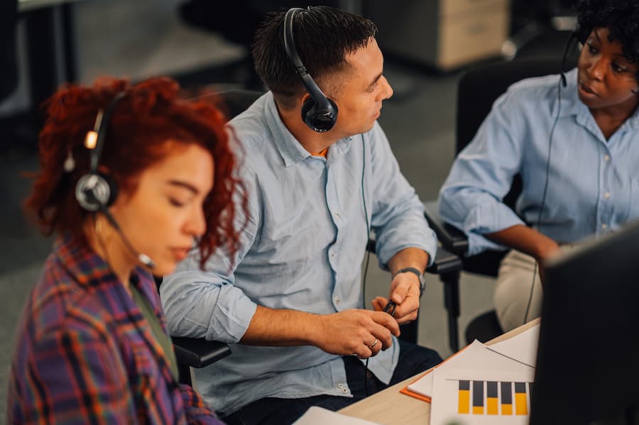 Customer Service Manager Discussing with team While Wearing Headsets at Work