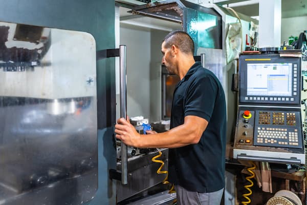 Technician using milling machine commands in a cnc factory