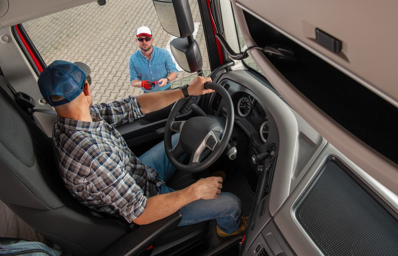 Truck Driver in Cab Talking to Another Man
