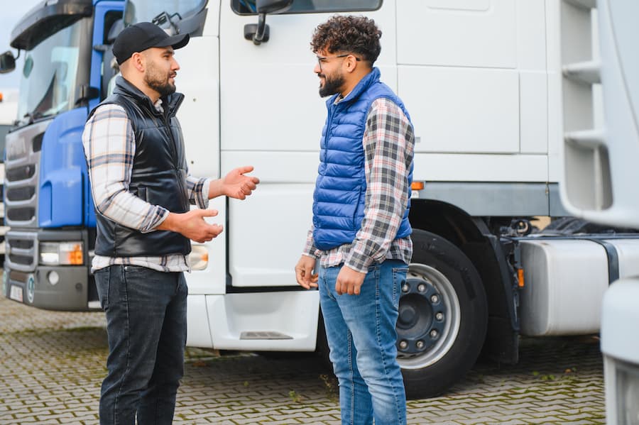 Two truck drivers talking next to their trucks